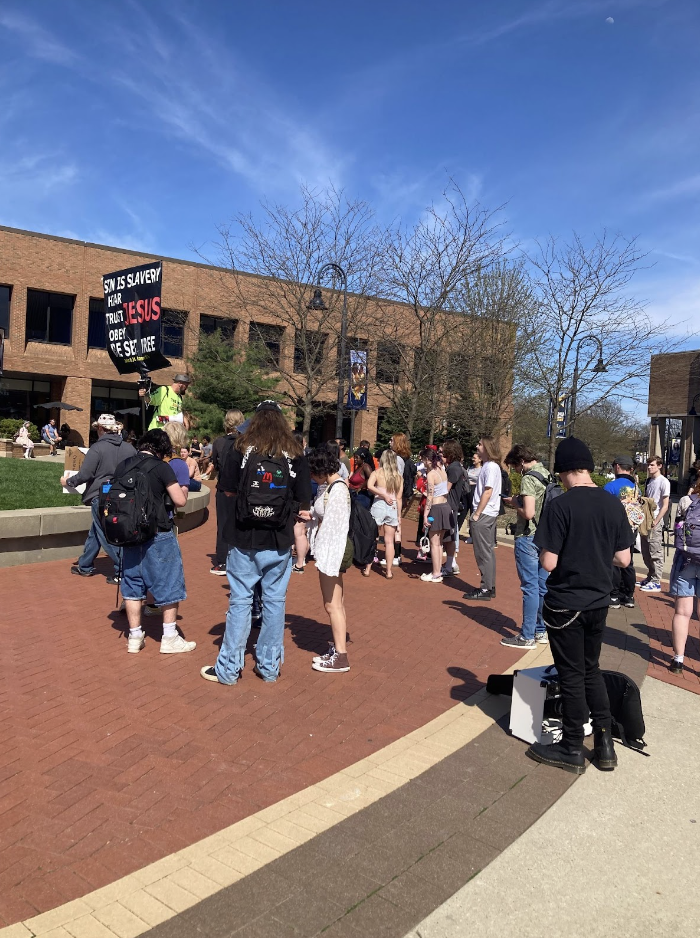 Students gather on Risman Plaza April 16 to listen to a speaker holding a sign about religion and sin who came to campus.

